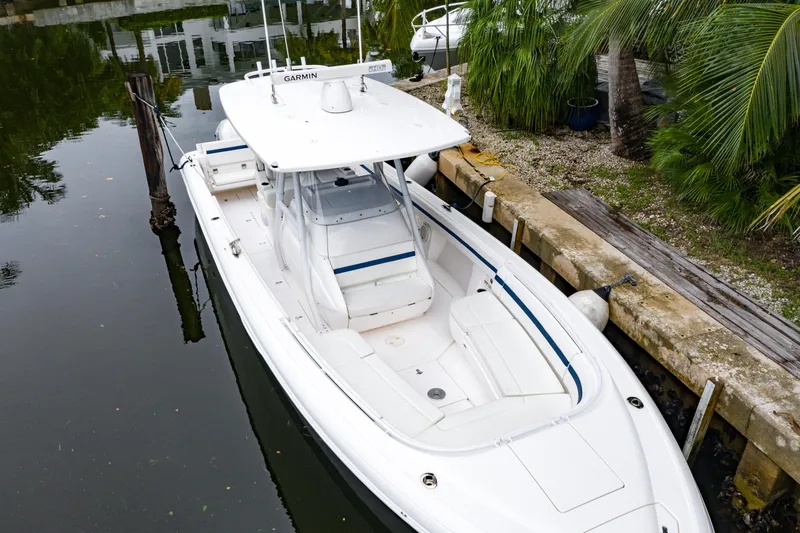 Slide: The Image of 2018 Intrepid 327 Center Console boat docked by palm trees. - 12
