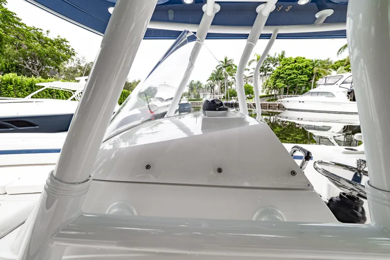 Slide: The Image of 2018 Intrepid 327 Center Console boat docked near lush greenery and other vessels. - 18