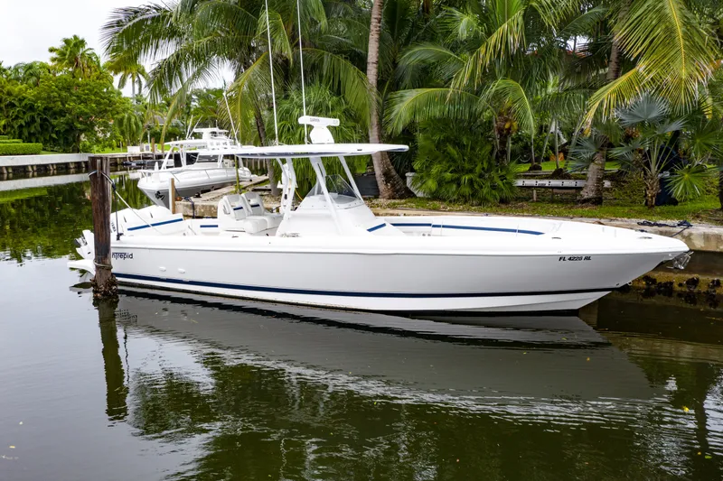 Slide: The Image of 2018 Intrepid 327 Center Console boat docked by palm trees. - 7