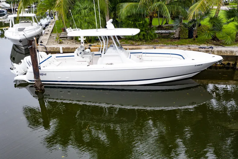 Slide: The Image of 2018 Intrepid 327 Center Console boat docked on calm water, surrounded by lush greenery. - 8
