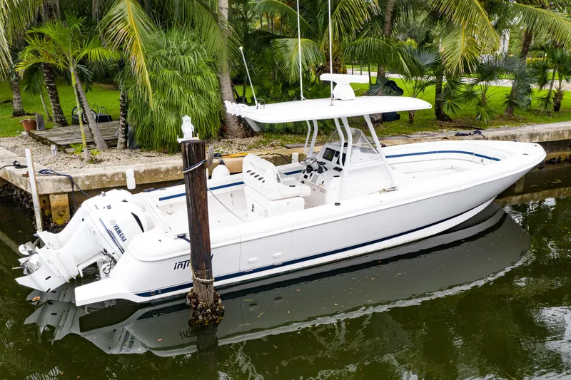 Slide: The Image of 2018 Intrepid 327 Center Console boat docked by lush greenery. - 9