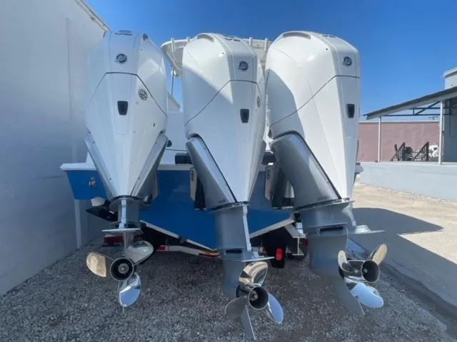 Slide: The Image of Triple outboard engines on a 2025 Contender 35 ST boat, parked on gravel. - 3