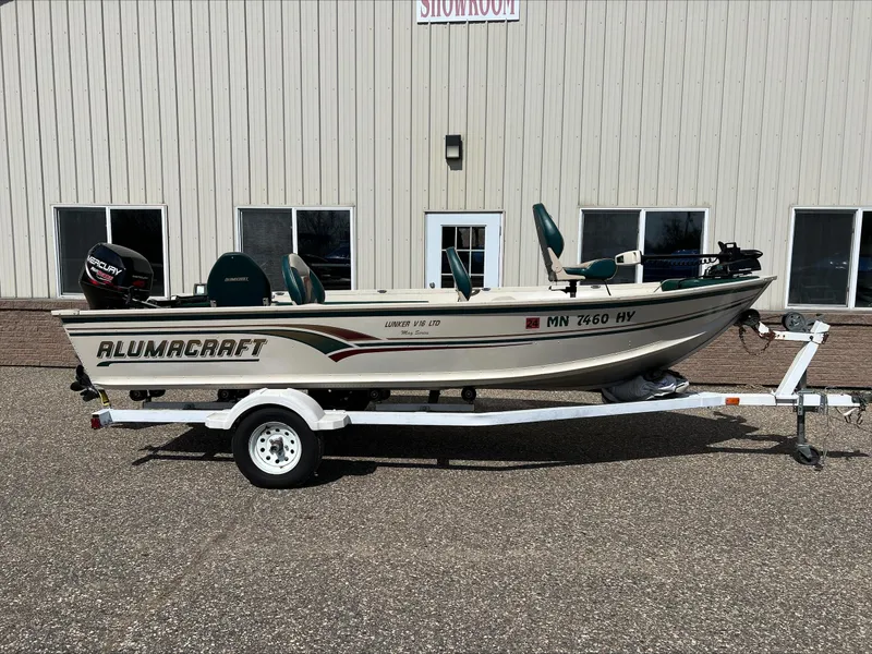 Slide: The Image of 2000 Alumacraft V 16 LTD boat on trailer, parked outside a showroom. - 0