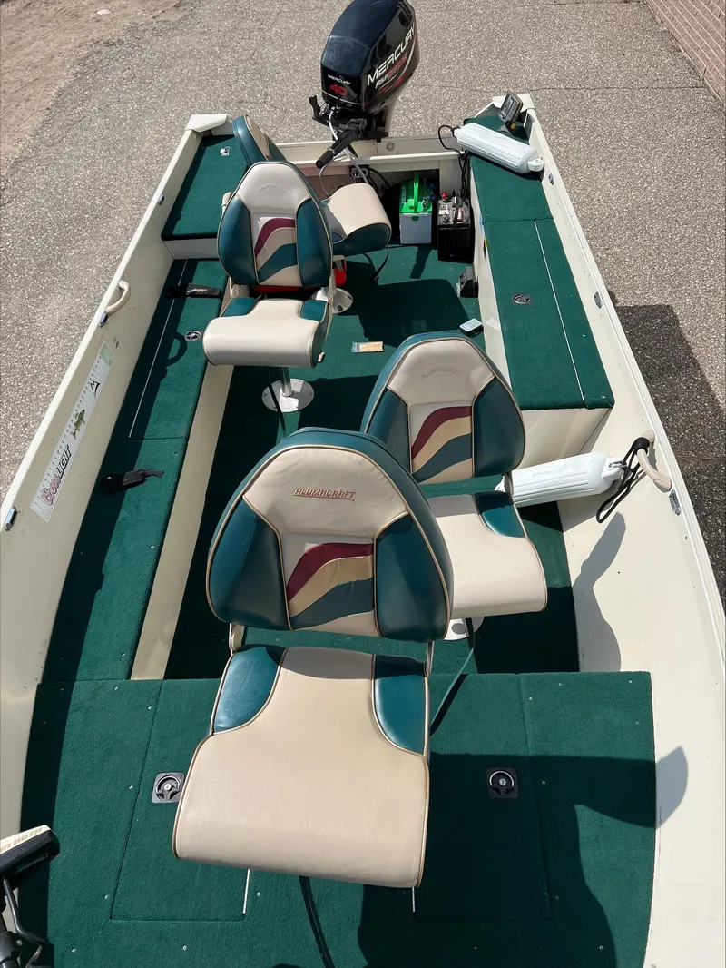 Slide: The Image of 2000 Alumacraft V 16 LTD boat with green carpet and three seats, featuring a Nissan outboard motor. - 7
