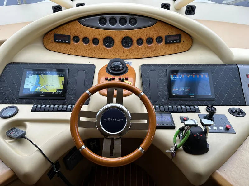Slide: The Image of 2008 Azimut 62 Evolution yacht dashboard with navigation screens and wooden steering wheel. - 2