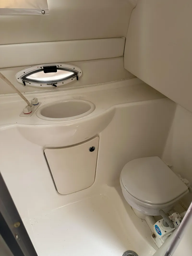 Slide: The Image of 2005 Bayliner 245 CIERA boat bathroom with sink, toilet, and porthole window. - 12