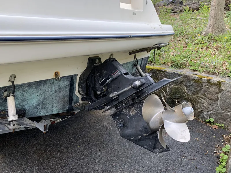 Slide: The Image of Bayliner 245 CIERA 2005 boat stern with propeller and outdrive, parked on pavement. - 2