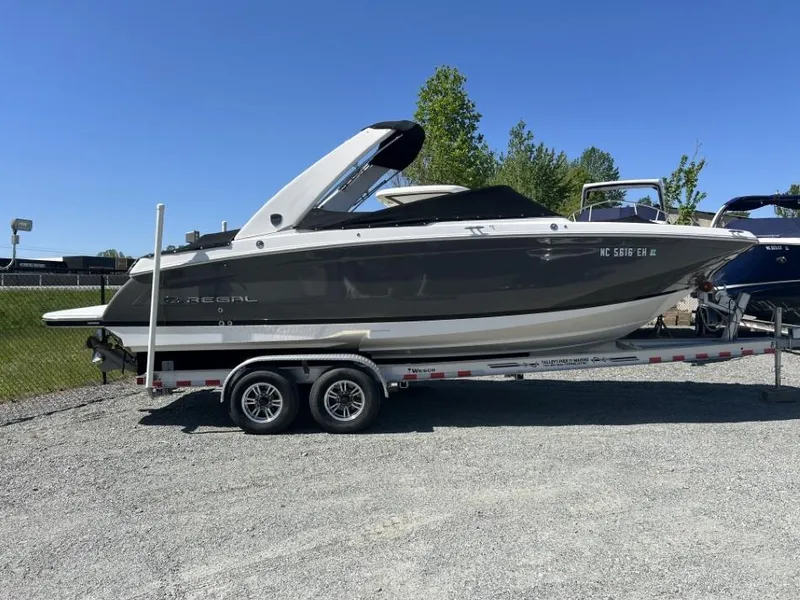 Slide: The Image of 2018 Regal 26 FasDeck boat on trailer, parked outdoors under clear blue sky. - 7