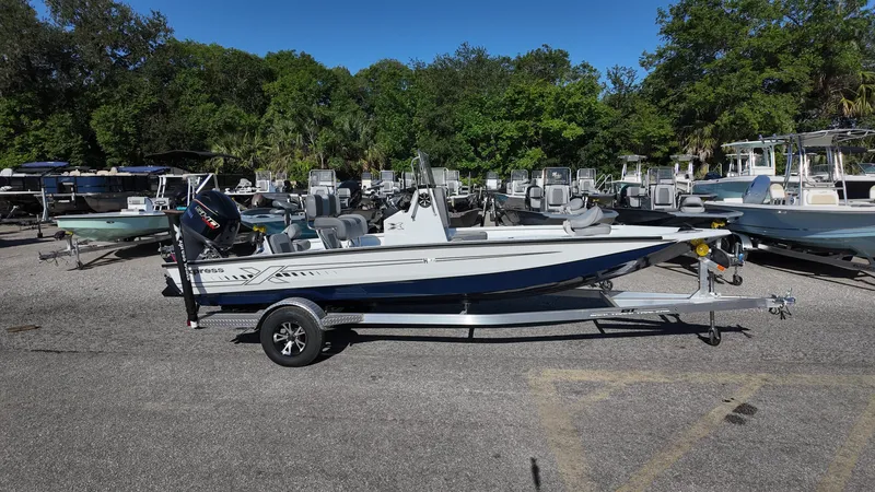 Slide: The Image of 2025 Xpress H20B boat on trailer in outdoor lot, surrounded by trees and other boats. - 10