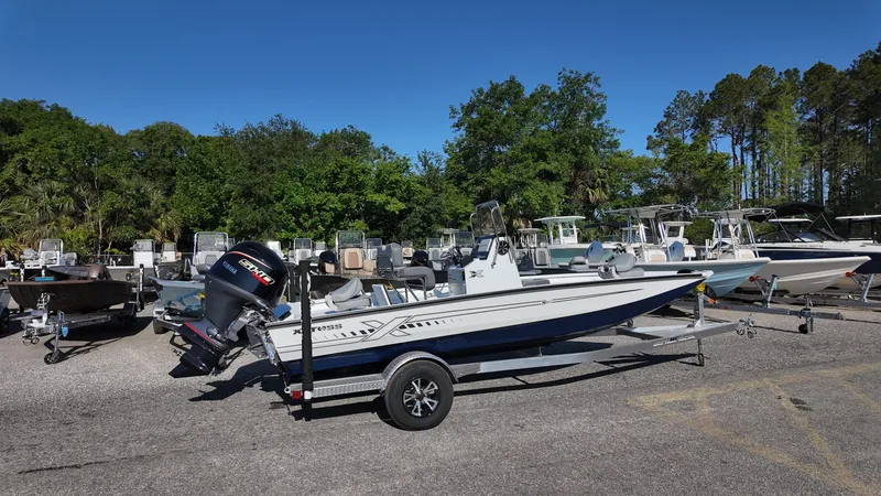 Slide: The Image of 2025 Xpress H20B boat on trailer in outdoor showroom with trees in background. - 16