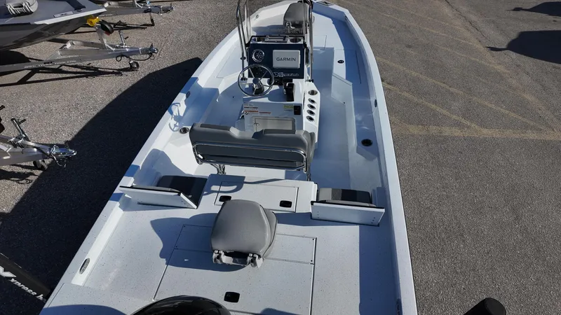 Slide: The Image of 2025 Xpress H20B boat interior with steering console and seating, parked on pavement. - 35