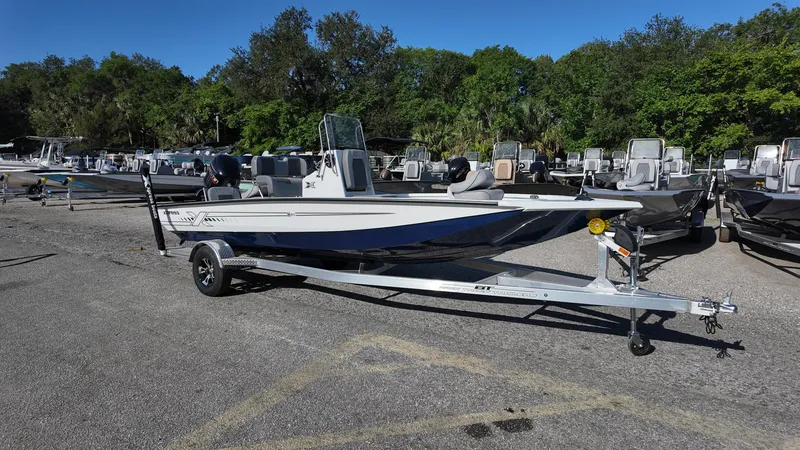 Slide: The Image of 2025 Xpress H20B boat on trailer in outdoor lot, surrounded by trees and other boats. - 5