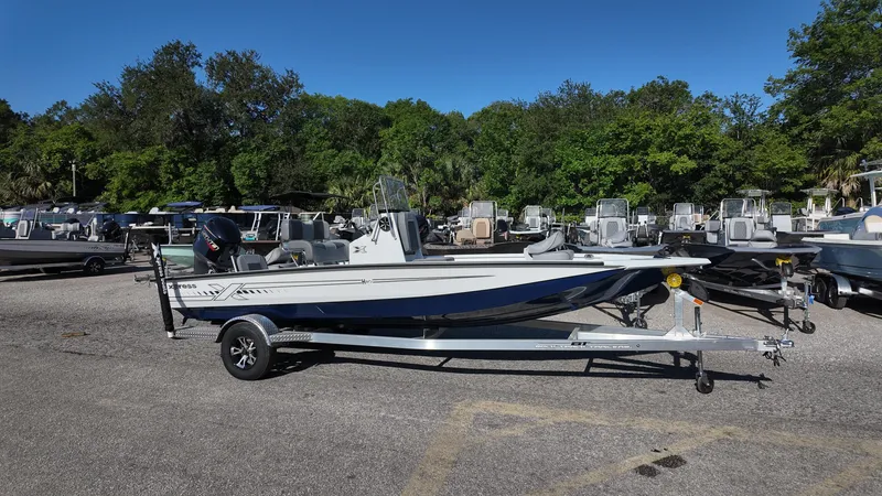 Slide: The Image of 2025 Xpress H20B boat on trailer in outdoor showroom, surrounded by trees and other boats. - 7