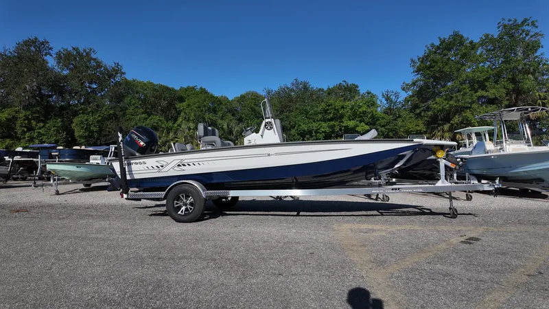 Slide: The Image of 2025 Xpress H20B boat on trailer in outdoor setting, surrounded by trees and other boats. - 9