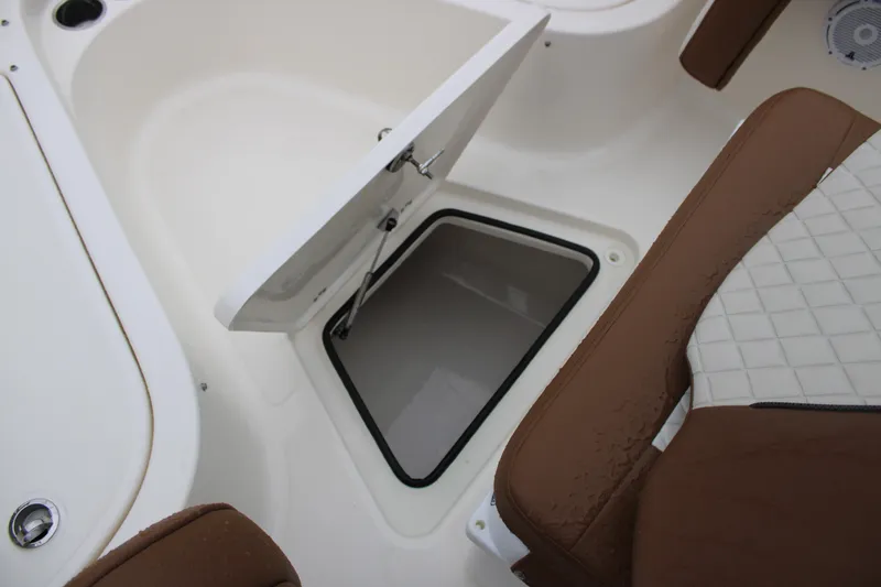 Slide: The Image of 2025 Pioneer 222 Sportfish boat storage compartment with open hatch and brown seating. - 11