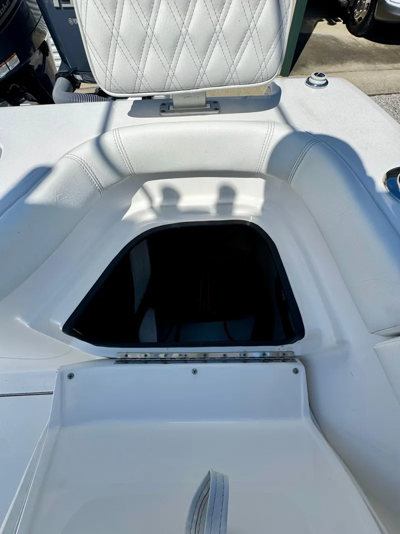 Slide: The Image of 2023 Contender 24S boat storage compartment with open hatch, featuring white cushioned seating. - 20