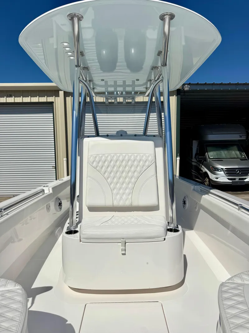 Slide: The Image of 2023 Contender 24S boat with sleek white seating and T-top, docked near storage units. - 8