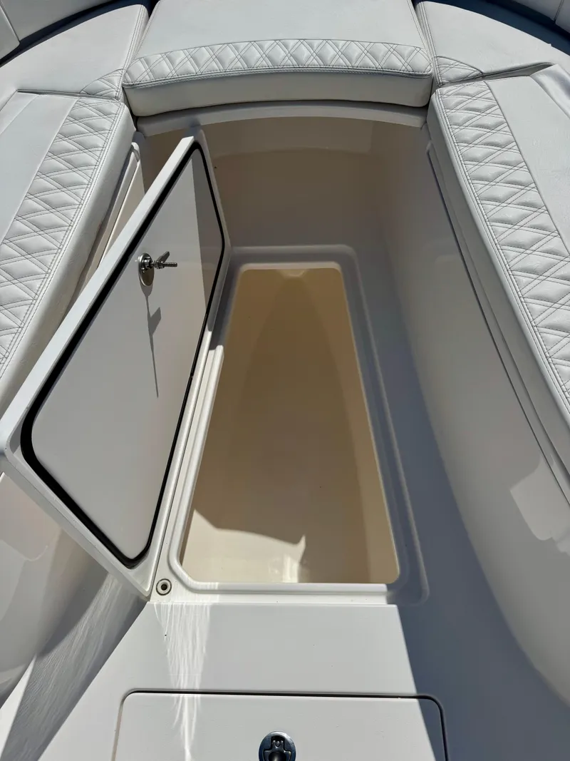Slide: The Image of 2023 Contender 24S boat storage compartment with open hatch, featuring quilted seating. - 9
