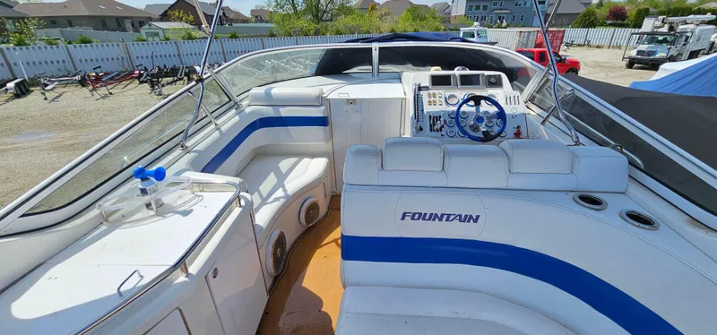 Slide: The Image of 2002 Fountain 38 Express Cruiser with white and blue seating, docked outdoors. - 25