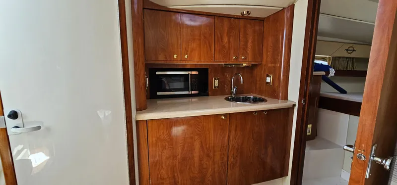 Slide: The Image of 2002 Fountain 38 Express Cruiser interior with kitchenette, wood cabinets, microwave, and sink. - 27