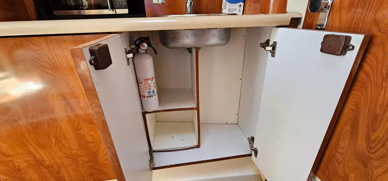 Slide: The Image of Open cabinet under sink in 2002 Fountain 38 Express Cruiser boat kitchen. - 31