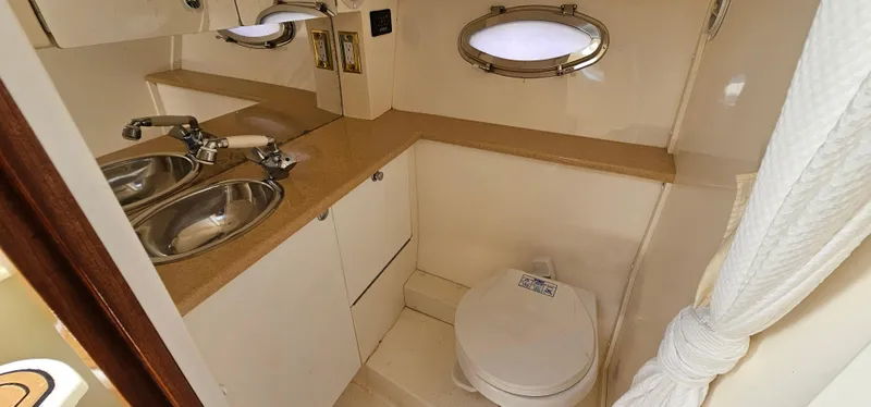 Slide: The Image of 2002 Fountain 38 Express Cruiser bathroom with sink, toilet, and porthole window. - 37
