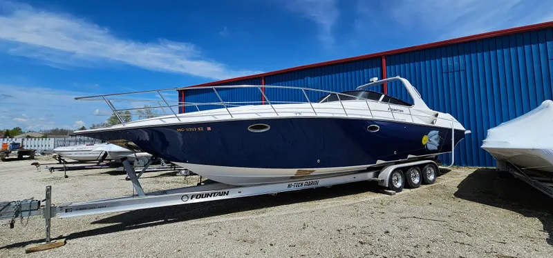 Slide: The Image of 2002 Fountain 38 Express Cruiser on trailer, parked outdoors near blue building. - 4