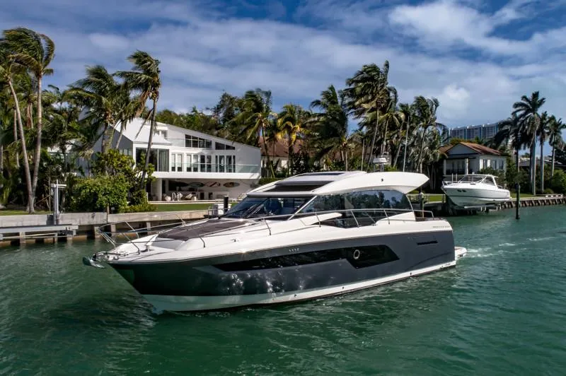 Slide: The Image of 2019 Prestige 520S yacht cruising near waterfront homes with palm trees. - 0
