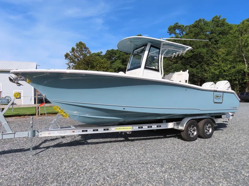 Slide: The Image of 2024 Sea Hunt Gamefish 25 boat on trailer, light blue hull, parked outdoors. - 0