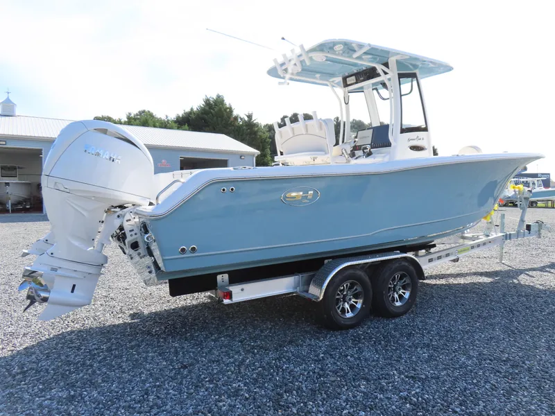 Slide: The Image of 2024 Sea Hunt Gamefish 25 boat on trailer, light blue hull, dual engines, outdoor setting. - 2