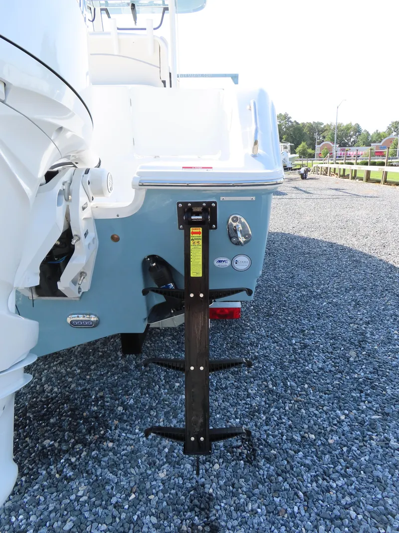 Slide: The Image of 2024 Sea Hunt Gamefish 25 boat rear view with ladder on gravel surface. - 6