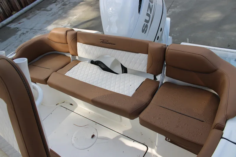 Slide: The Image of 2025 Pioneer 222 Islander boat seating with brown and white upholstery, featuring a Suzuki engine. - 13