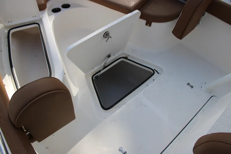 Slide: The Image of 2025 Pioneer 222 Islander boat interior with open storage compartments and brown seating. - 8