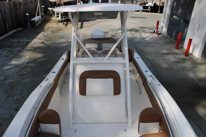 Slide: The Image of 2025 Pioneer 222 Islander boat with white and brown seating, docked outdoors. - 9