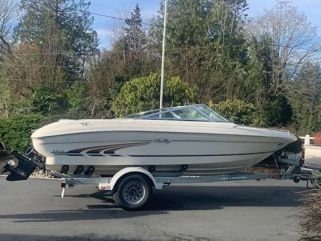 Slide: The Image of 1998 Sea Ray 185 Bow Rider on trailer, parked outdoors with trees in background. - 1