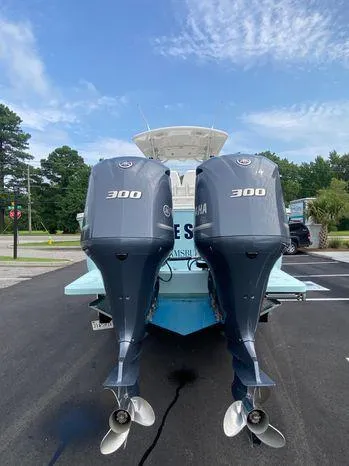 Slide: The Image of 2013 Regulator 28 Forward Seating boat with twin Yamaha 300 engines, parked outdoors. - 2