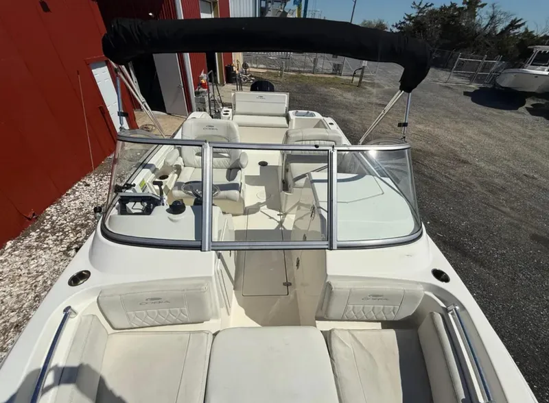 Slide: The Image of 2021 Cobia 220 Dual Console boat with white seating and black canopy, docked outdoors. - 14