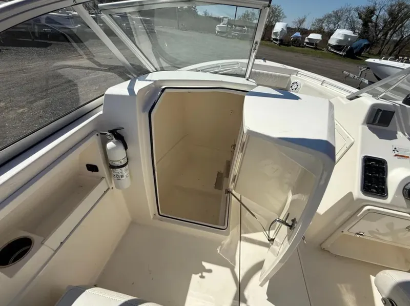 Slide: The Image of 2021 Cobia 220 Dual Console boat interior with open storage compartment and fire extinguisher. - 16