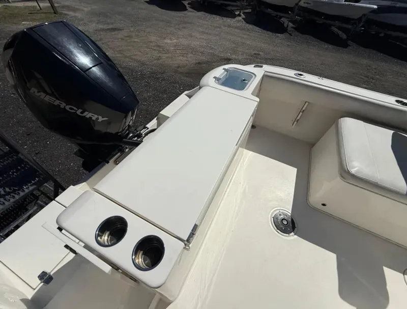 Slide: The Image of 2021 Cobia 220 Dual Console boat with Mercury engine, featuring cup holders and seating area. - 18