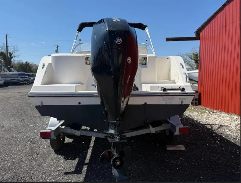 Slide: The Image of 2021 Cobia 220 Dual Console boat with outboard motor, parked near a red building. - 4
