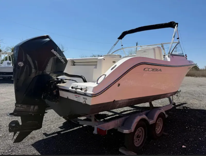 Slide: The Image of 2021 Cobia 220 Dual Console boat on trailer with Mercury outboard engine. - 5