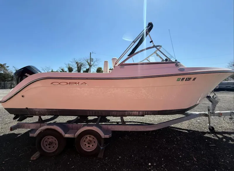 Slide: The Image of 2021 Cobia 220 Dual Console boat on trailer, side view under clear sky. - 6
