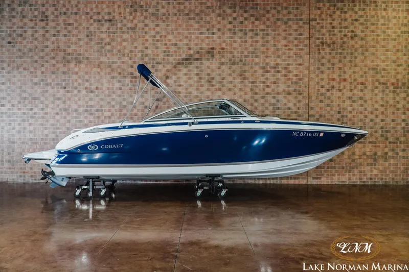 Slide: The Image of 2013 Cobalt 232 boat in showroom, blue and white design, displayed at Lake Norman Marina. - 1