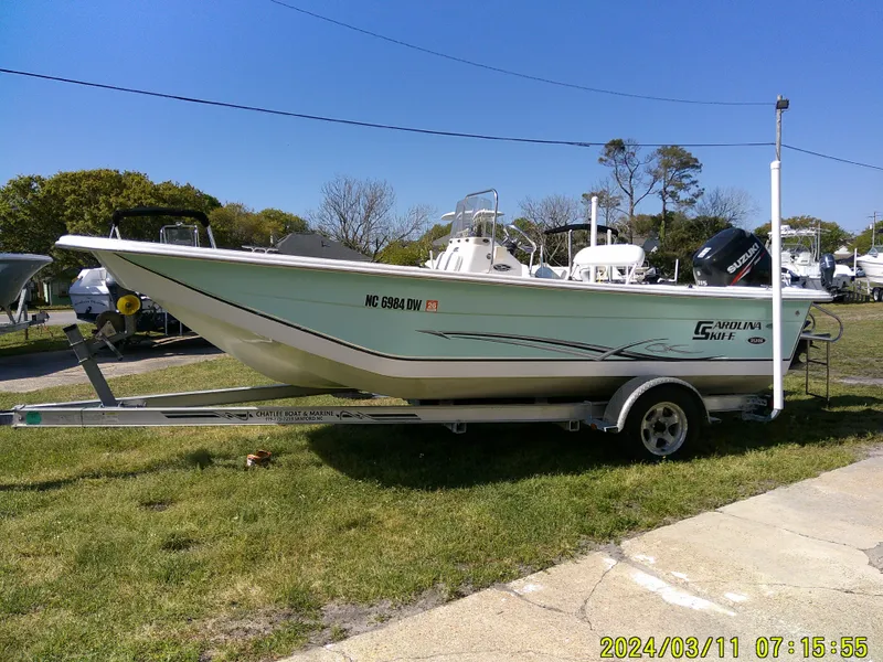 Slide: The Image of 2012 Carolina Skiff 198 DLV boat on trailer, parked outdoors on grass. - 1