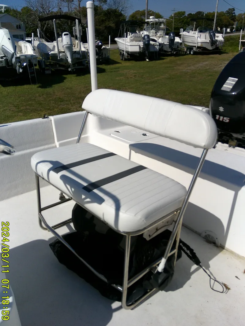 Slide: The Image of 2012 Carolina Skiff 198 DLV boat with white seating and outboard motor in a marina. - 13