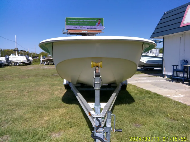 Slide: The Image of 2012 Carolina Skiff 198 DLV boat on trailer, parked on grass under clear blue sky. - 5