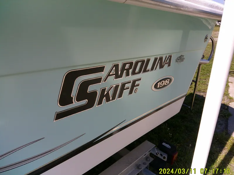 Slide: The Image of 2012 Carolina Skiff 198 DLV boat side view with logo and model details. - 6