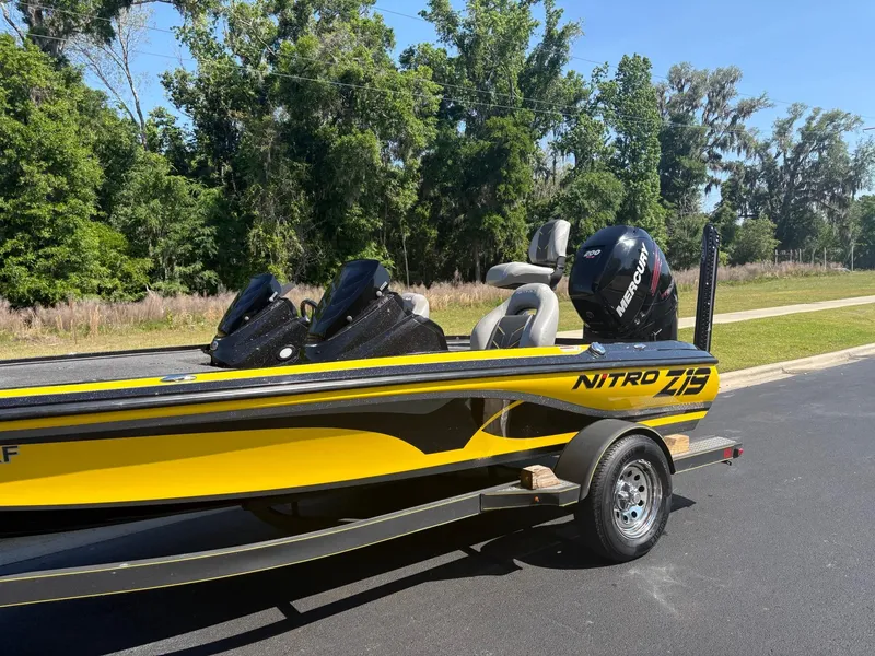 Slide: The Image of 2017 Nitro Z19 boat with Mercury engine on a trailer, parked near trees. - 3