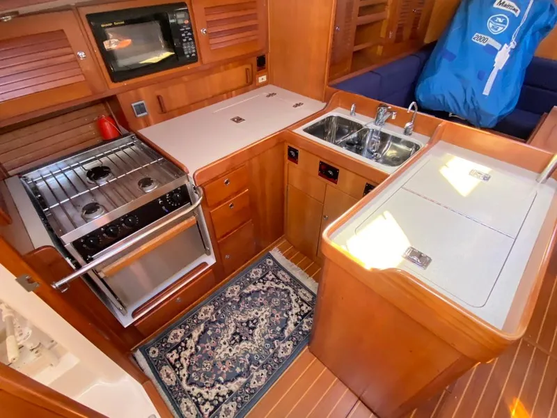 Slide: The Image of Cozy 2000 J Boats J/46 yacht kitchen with stove, sink, and wooden cabinetry. - 33