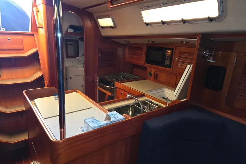 Slide: The Image of Interior of 2000 J Boats J/46 sailboat, featuring a well-equipped galley and wooden cabinetry. - 56